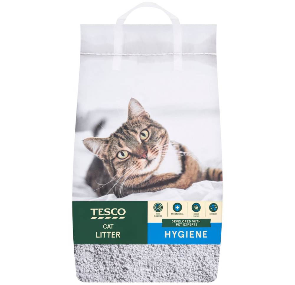 A bag of Tesco cat litter featuring a friendly tabby cat lying on a soft surface, emphasizing hygiene and cleanliness for pets.