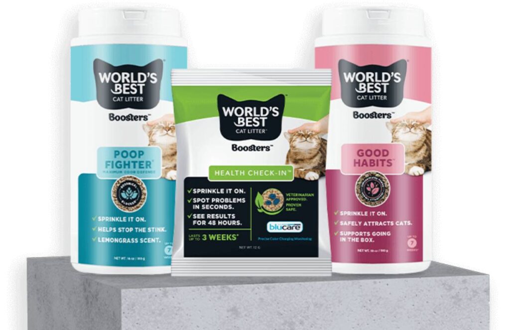 Three containers of 'Worlds Best Cat Litter' boosters: Poop Fighter, Health Check-In, and Good Habits, displayed on a concrete pedestal.