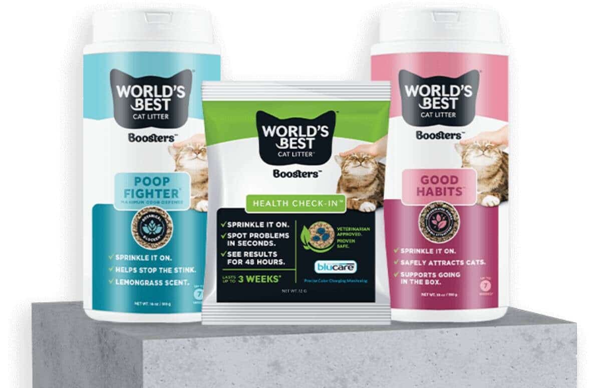 Three containers of 'Worlds Best Cat Litter' boosters: Poop Fighter, Health Check-In, and Good Habits, displayed on a concrete pedestal.